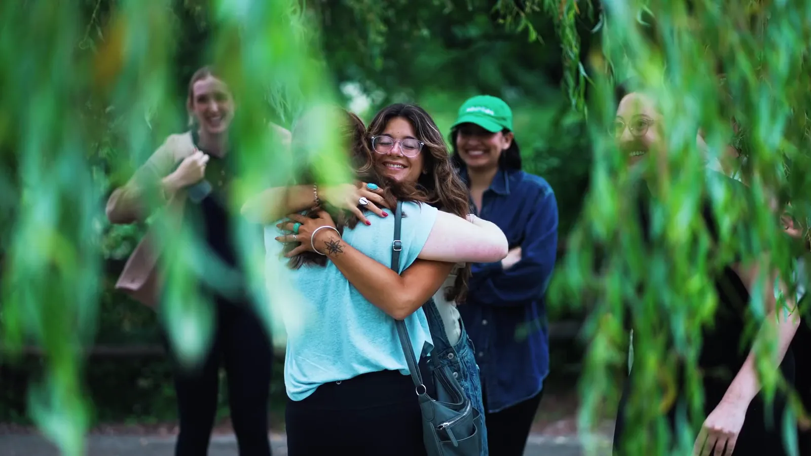 Two colleagues hugging under willow branches at the Global Retreat