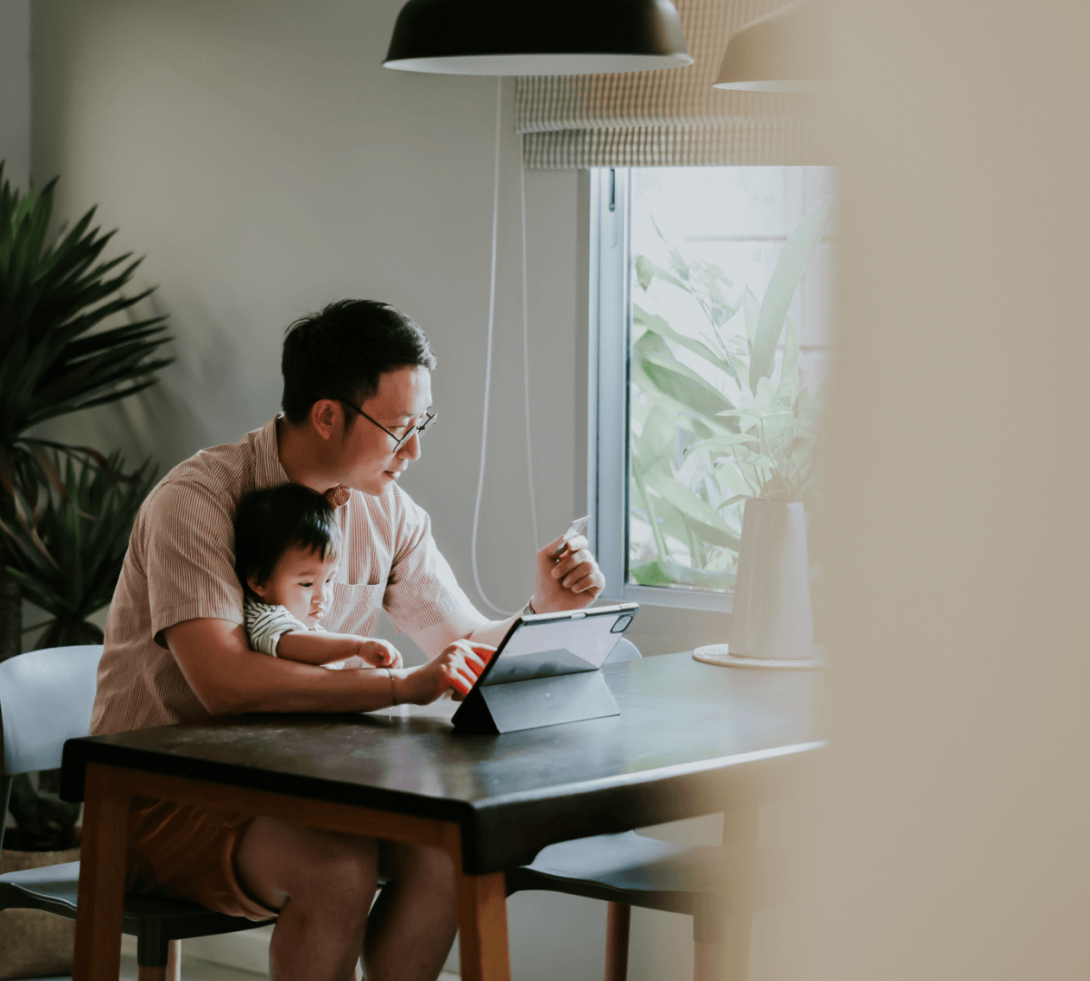 Man holding baby and working on computer