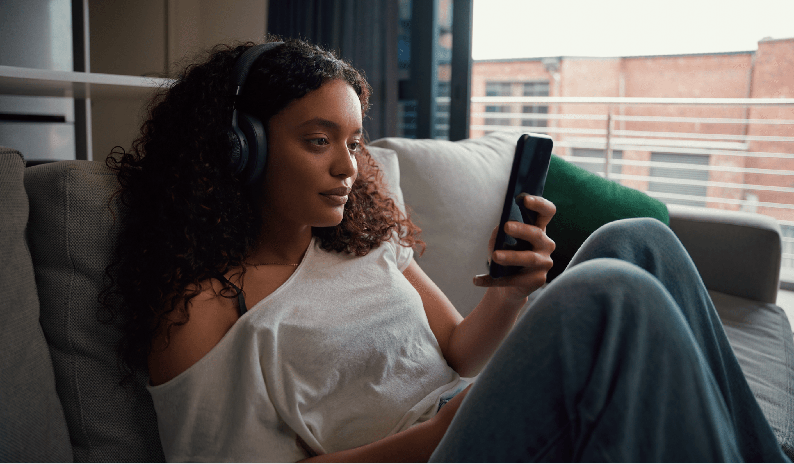 A woman with headphones on looking at her phone
